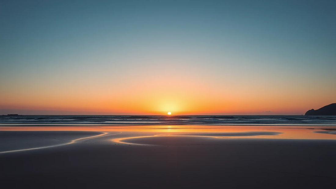 Calm Australian ocean sunrise with orange-pink sky reflected on wet sand.