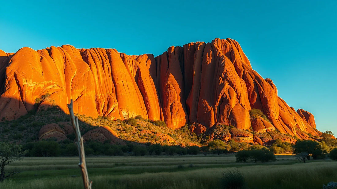 Arnhem Land sandstone escarpment in warm late dry-season light above a green floodplain fringe.